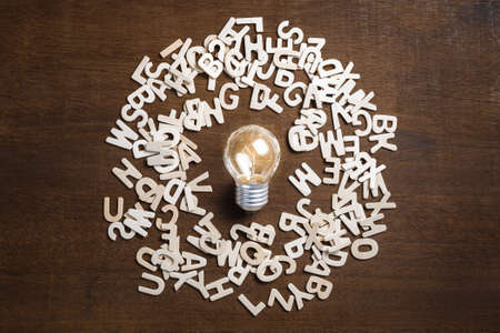 Small light bulb glowing at the center among the wood lettersの写真素材