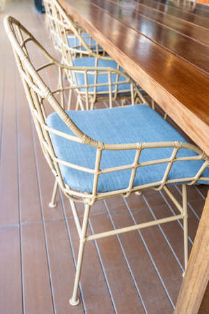 Metal chair binding by plastic stripe on frame with blue cushion at wood terrace outside the houseの写真素材