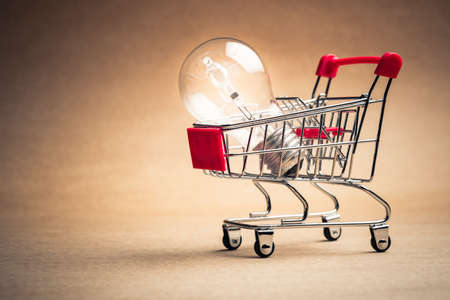 Small shopping cart with glowing light bulb for shopping idea, smart buying or energy saving conceptの写真素材