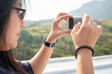 Closeup hand of asian woman use smartphone to take the photo of countryside view