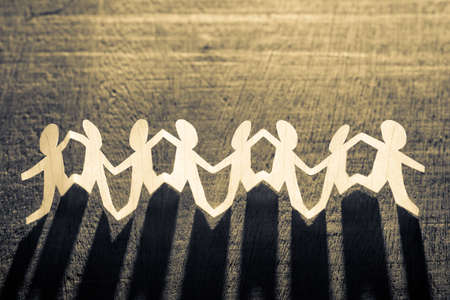 Paper human chain against the light on wood background