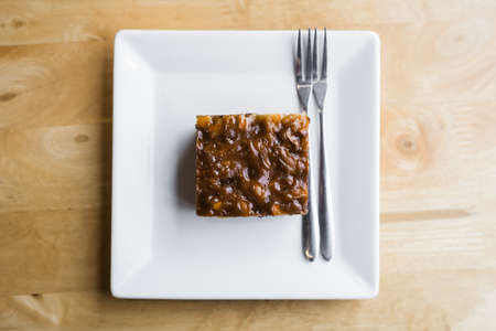 Small piece of brownie cake in white plate on wood tableの写真素材