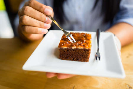 Closeup hand of woman going to eat the brownie cakeの写真素材