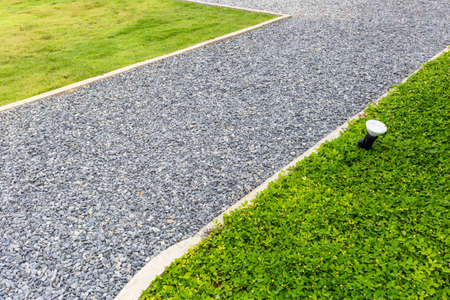 Pebbles walkway in the garden with part of lawn and green plantの写真素材