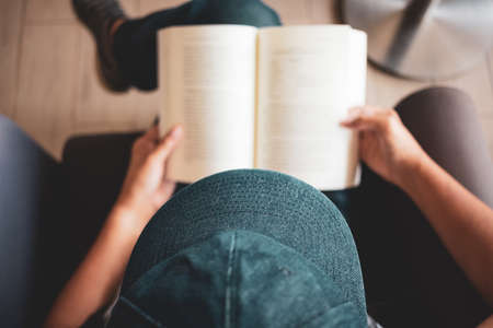 Woman read the pocket book on the armchair, top view or over head shot of woman wearing hat rest the book on her lap to readの写真素材
