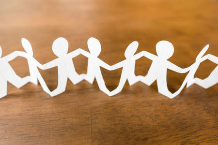 Closeup paper human chain on wood backgroundの写真素材