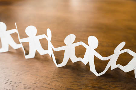 Closeup paper human chain on wood backgroundの写真素材