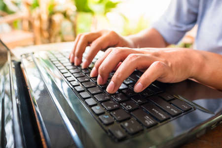 Closeup woman hand typing on laptop keyboard, working in the backyrad at home
