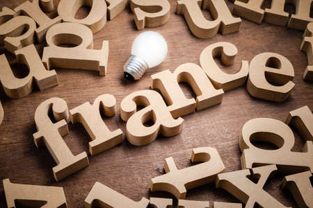 France wood alphabet in scattered letters with light bulb, France education conceptの写真素材