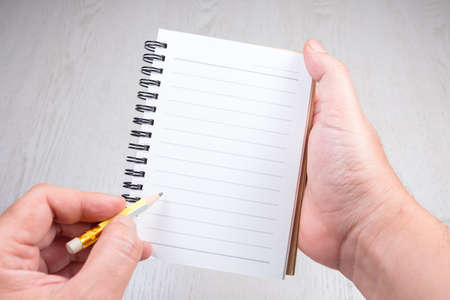 Haand with the notebook and pencil on empty white sheet as space for textの写真素材