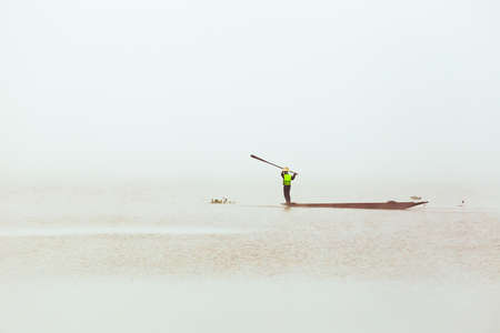 Fisherman use the paddle hit the water to chase the fish go to the fishing netの写真素材