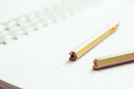 Closeup broken pencil on opened notebook, mistake in writing conceptの写真素材