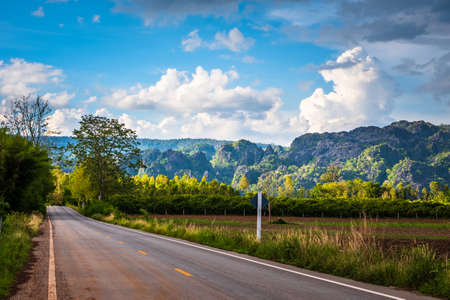 Beautiful mountain view on the country road along the farmland at Noen Maprang, Phitsanulok province of Thailandの写真素材
