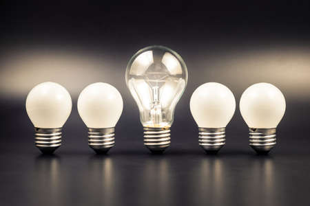 Bigger light bulb glowing in the middle of the row of small light bulbs, leader light bulbの写真素材