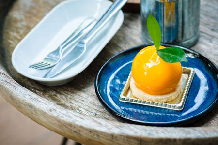 Orange mousse cake in blue ceramic plate on the old style wood table
