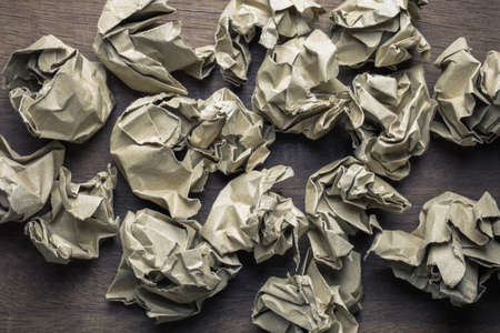 Many crumpled brown paper balls on wood table, create writing work conceptの写真素材