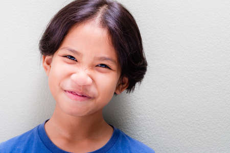 Closeup face of nine years old girl that try to stop laughing but still funny expression, pretty...