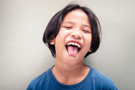 Child is fun laughing and show her tongue, nine years old Thai girlの写真素材