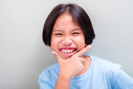 Nine years old girl has a big smile and acting hand on her chin to show clean teeth healthの写真素材