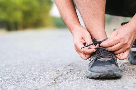 Closeup hand tying rope of the running shoe on the road