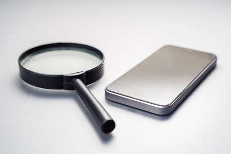 Smart phone and magnifying glass, searching information or others mobile detection concept