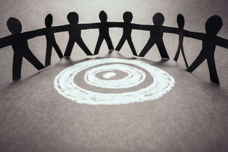 Paper human team stand around the target sketched by chalk, all for one mission, teamwork for...