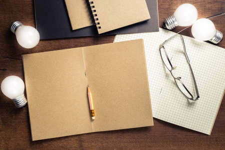 Opened notebooks with glowing small light bulbs on the desk, start creative writing conceptの写真素材
