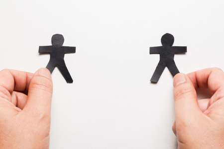 Hand split a two paper human dolls stay away from each other, human or social distancing
