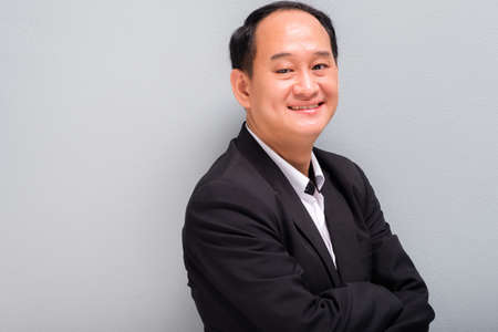 Portrait of Asian businessman smiling at green wall background, Thai insurance agent and finance...