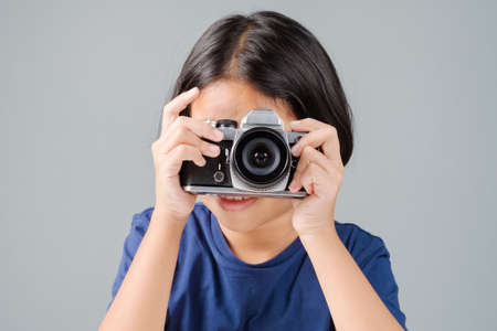 Nine years old girl act like a young photographer taking picture with old style film cameraの写真素材