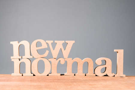 NEW NORMAL word by wood alphabets set on wood board and light green wallの写真素材