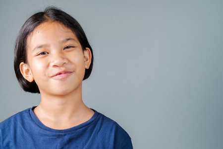 Nine years old girl looking at camera and smile on gray wall background