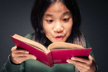 Child girl open old book and be excited to find something on the page, enjoy reading expression
