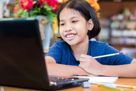 Child girl smiling while watching the content on computer laptop, online education conceptの写真素材