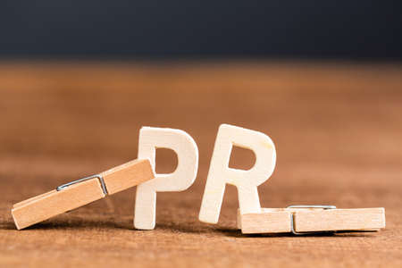 PR acronym or Public Relation by wooden alphabets pinched in wooden clothespinの写真素材