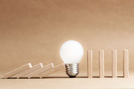 Glowing light bulb block the falling domino in a row, problem and solution, creative idea to stop...