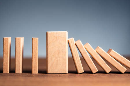 Closeup thick domino wood block in a row stop the falling, be stable in crisis, business solution conceptの写真素材