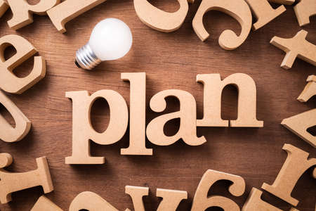 PLAN block wood word arranged in the scattered alphabets with glowing light bulb, smart and success...