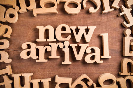 NEW ARRIVAL block wood word arranged in the scattered alphabets on the table