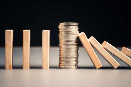 Closeup heap of coins in a row of domino that stop the collapseの写真素材