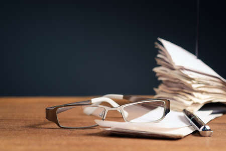 Closeup eyeglasses and pen on the bills with many bills left in the paper nail