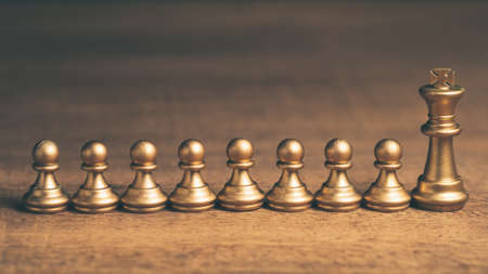 Golden king chess and row of pawns on wood backgroundの写真素材