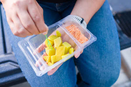Closeup woman going to eat the pickled mango with chili and salt in the plastic package, favourite food in Thailand to fix the drowsy and be refresh during the long drive on the roadの写真素材