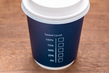 Portable coffee cup with text : Sweet Level and percentage check box, on wood table, concept for...