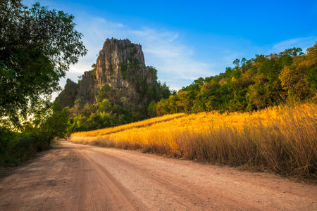 Beautiful limestone mountain and field at sunset on the dirt road in countryside, Noen Maprang, Phitsanulok, Thailandの写真素材