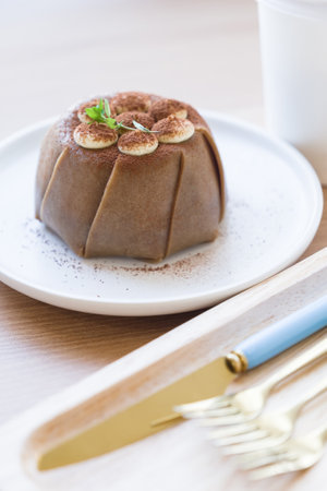 Tiramisu soft cake in round white plate with part of knife and forksの写真素材