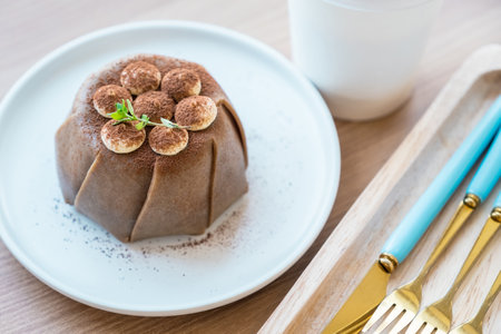 Tiramisu soft cake in round white plate with part of knife and forks