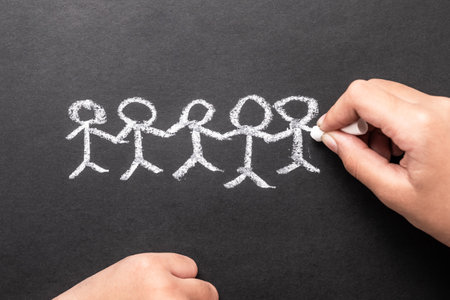 Closeup child's hand drawing human holding hand together with chalk, symbol of team, staff, relation of human or family conceptの写真素材
