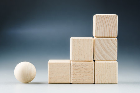 Wooden cubes arranged as step stairs with wooden sphere ball as subject to move up to success, career progress and goal settingの写真素材