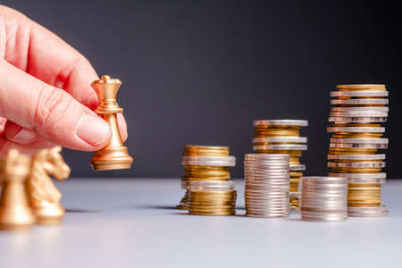 Hand move the queen chess encounter the group of money coins heap. Financial game strategy, financial planning. Business competition conceptの写真素材